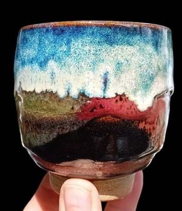 Stoneware cup with layered blue, white, green, red and dark brown glazes evoking mountains, by Andrew Richards Ceramics