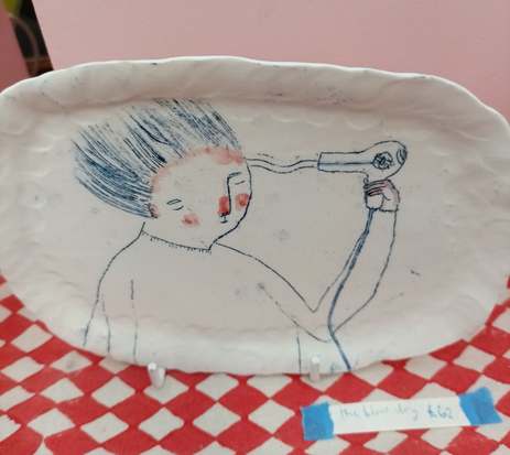 Porcelain platter by Becca Brown with a blue line drawing of a person blow-drying their hair