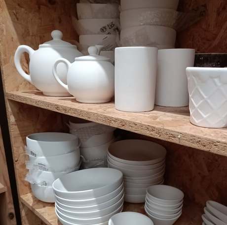 Shelves of plain white bisque teapots, bowls, mugs and plates waiting to be painted