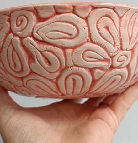 Handmade bowl with raised coil patterns and a pink glaze pooling in the grooves