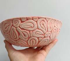 Handmade bowl with raised coil patterns and a pink glaze pooling in the grooves