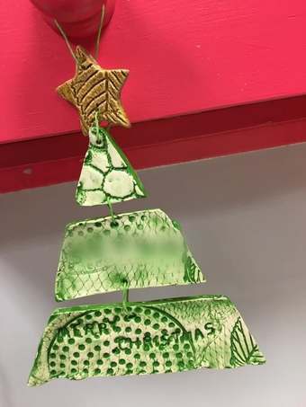 Handmade green-glazed clay Christmas tree decoration stamped ‘Merry Christmas’, with a textured star on top