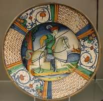 Italian Renaissance maiolica dish painted with a horseman carrying a lance, inside a rim of scale and scroll patterns.