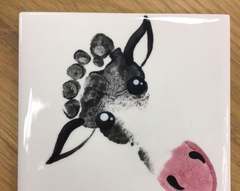 Ceramic tile with a child’s footprint painted as a cow’s face