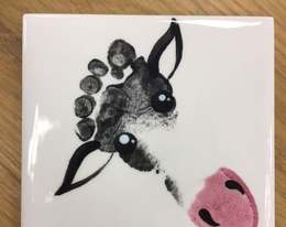 Ceramic tile with a child’s footprint painted as a cow’s face