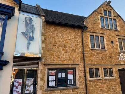 Harborough Theatre’s ironstone frontage, with the angular Harlequin sculpture on a panel above the neighbouring display window.