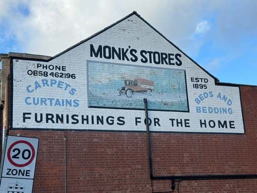 Painted ‘Monk’s Stores – Furnishings for the Home’ advertising sign, established 1895, on a red-brick gable end
