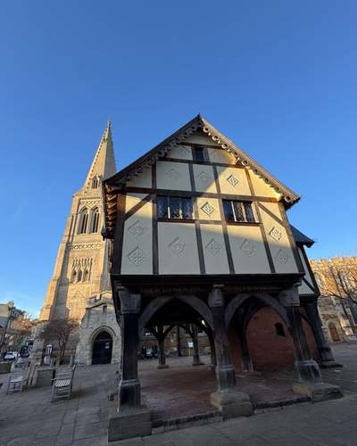 The Old Grammar School in Market Harborough, raised on oak posts, with St Dionysius church spire behind