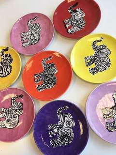 Eight brightly glazed plates, each painted with a black-and-white patterned elephant