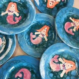 Blue bubble-glazed plates, each painted with an orange-haired mermaid