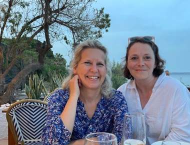 The two retreat teachers smiling together at a seaside restaurant table at dusk