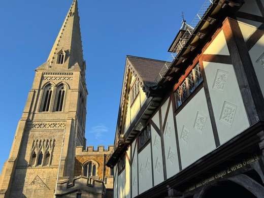 St Dionysius Church spire beside the timber-framed Old Grammar School in Market Harborough under a blue sky