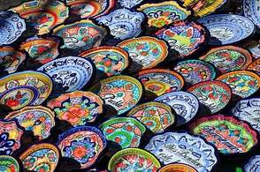 Rows of brightly hand-painted Mexican Talavera bowls, many lettered ‘Puebla’, laid out in the sun.
