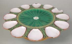 Victorian majolica oyster plate with white shell-shaped wells around a glossy green fluted centre.
